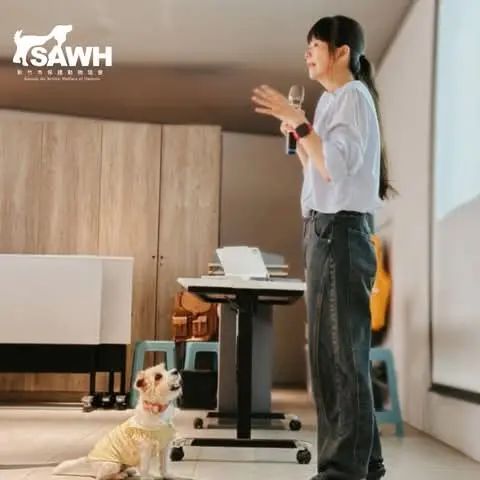 A speaker and a dog teaching assistant at an owner talk