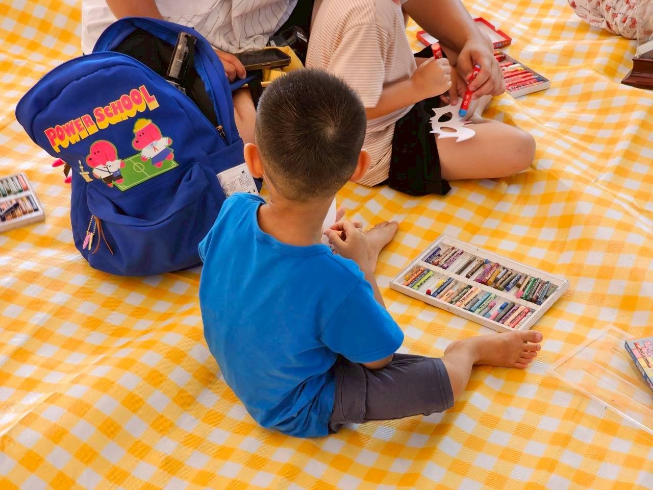 A child drawing on a picnic mat
